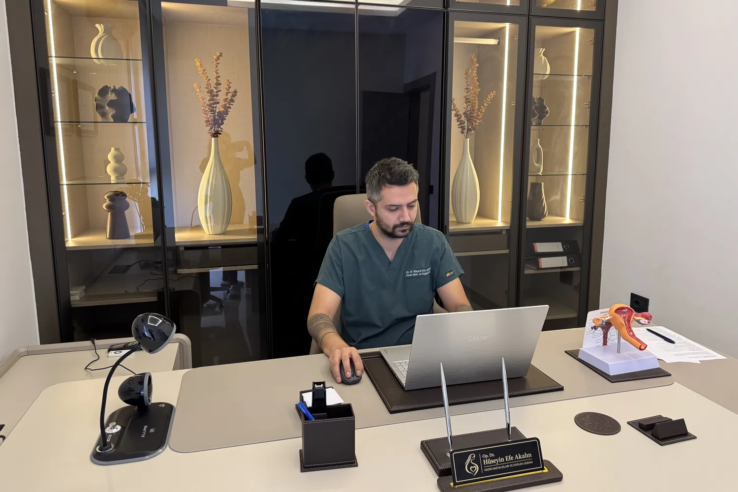 Op. Dr. Hüseyin Efe Akalın working at his desk in the consultation room