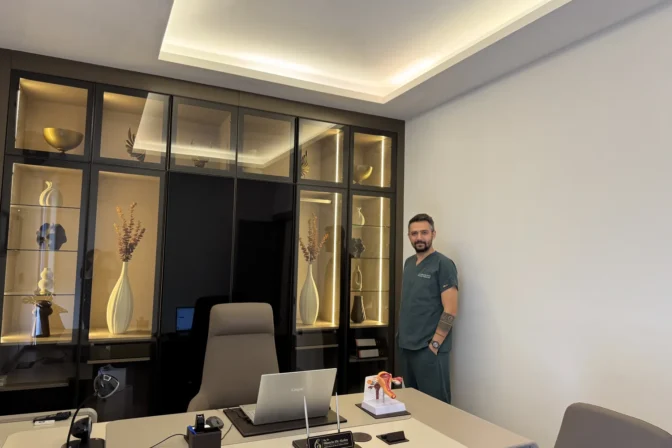 Op. Dr. Hüseyin Efe Akalın standing in his office, full room view