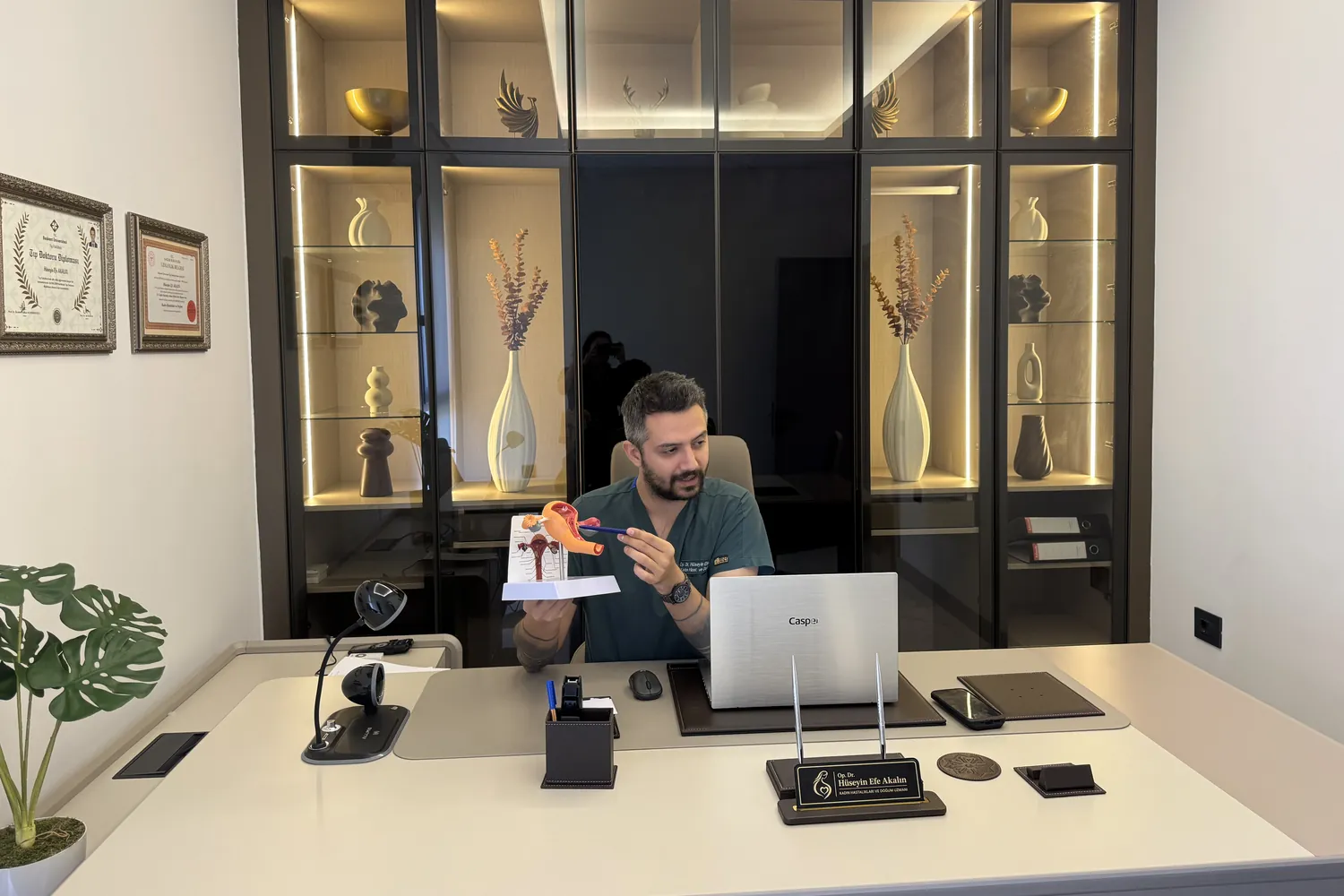 Op. Dr. Hüseyin Efe Akalın showing a uterus model at the consultation desk