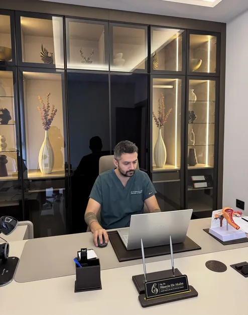 Op. Dr. Hüseyin Efe Akalın working at his desk in the clinic, portrait view