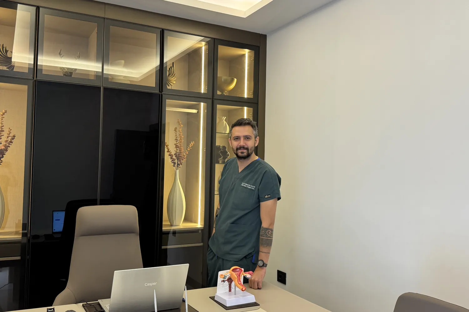 Op. Dr. Hüseyin Efe Akalın standing beside his desk in the consultation room