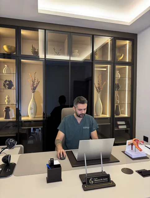 Op. Dr. Hüseyin Efe Akalın at his desk in the clinic, front view